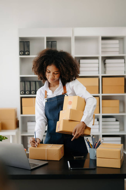  African woman working at home office -packaging and delivery,  e-commerce concept - 写真・画像