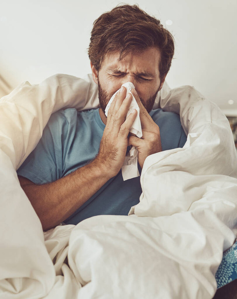 Man, blowing nose and sneeze, sick with allergies or influenza, virus and bacteria with health fail at home. Toilet paper, illness and healthcare with crisis or disaster, medical condition and flu. - Photo, Image
