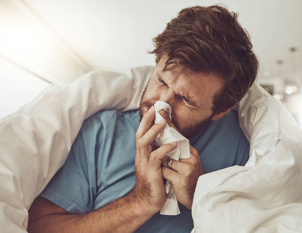 Man, blowing nose and sneezing, sick with allergies or influenza, virus and bacteria with health fail at home. Toilet paper, illness and healthcare with crisis or blanket, medical condition and flu. - Photo, Image