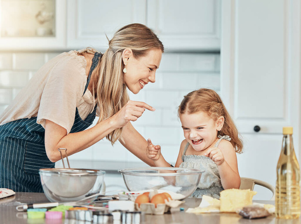 Mom, girl kid and teaching for baking, development and laugh with bonding, love and care in family home. Cooking, funny mother and daughter with bowl, flour or eggs on table, kitchen or help for food. - Photo, Image