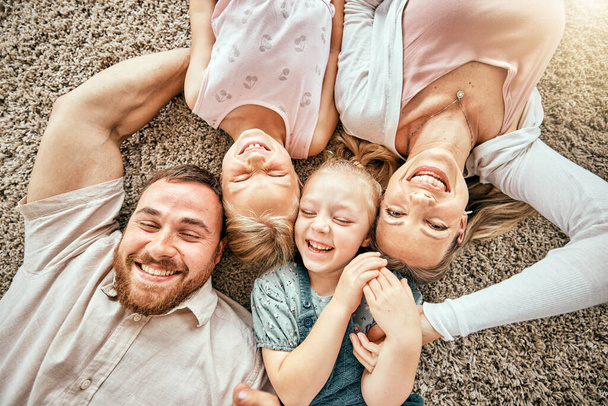 Smile, portrait and kids with parents in the living room bonding and relaxing together at home. Happy, love and girl children laying with mother and father from Australia on floor in lounge at house - Фото, зображення