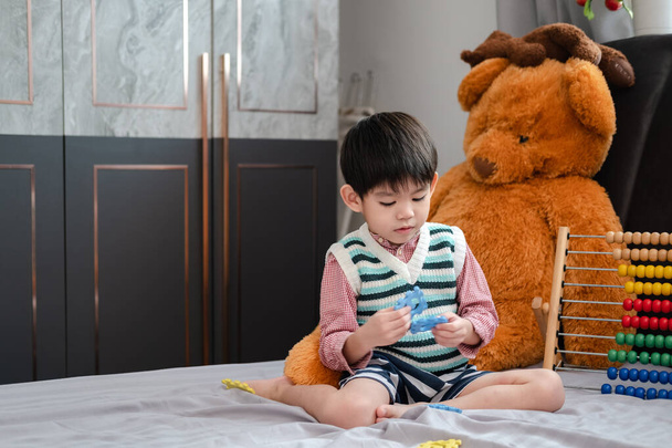 Asian boy playing with jigsaw puzzles on the bed joyfully - Photo, Image