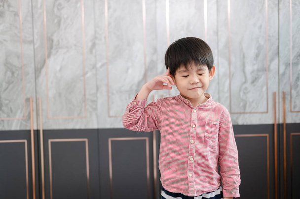 アジアの少年は頭を指差す手で立っている. 何かを考えているふりをする - 写真・画像
