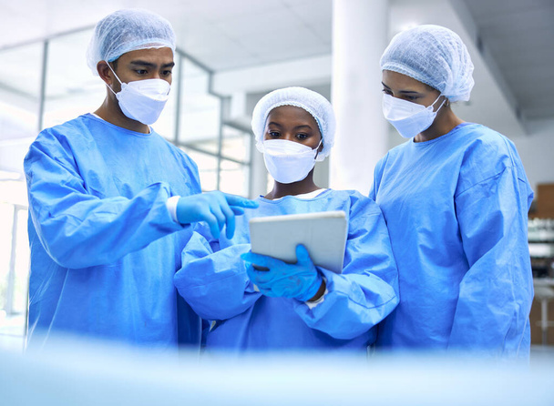 Γιατρός, tablet και ομάδα με μάσκα σε συνάντηση, σχεδιασμό ή συνεργασία για χειρουργική επέμβαση στο νοσοκομείο. Ομάδα ιατρικού προσωπικού με τεχνολογία στην ομαδική εργασία, συμβουλευτική ή στρατηγική υγειονομικής περίθαλψης στην κλινική. - Φωτογραφία, εικόνα