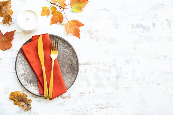 Autumn table setting. Cozy fall decorations, craft plate and golden cutlery on white background. - Photo, Image