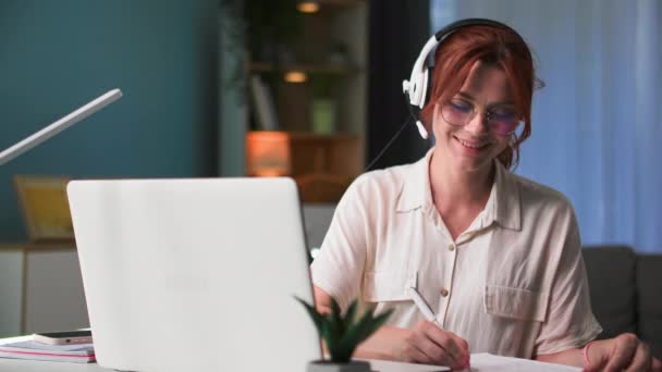 freelancer, γυναίκα που εργάζονται εξ αποστάσεως στην υποστήριξη πελατών τεχνολογίας και μιλάμε χρησιμοποιώντας ακουστικά, ενώ κάθεται στο τραπέζι στο σπίτι - Πλάνα, βίντεο