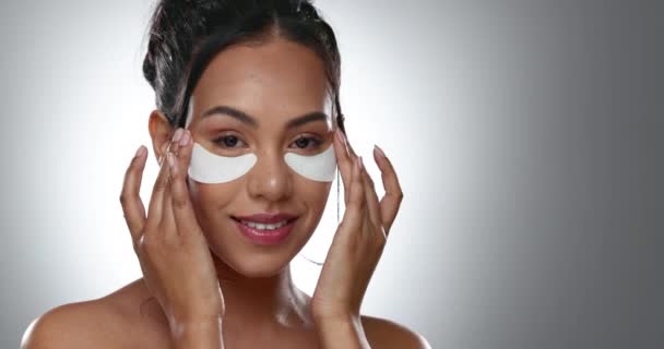 Woman, eye and patch for treatment in studio, face and mockup for skincare on gray background. Female model, person and smile with product for beauty with glow, hydration or moisturizer in anti aging. - Footage, Video