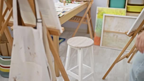 jong blond vrouw kunstenaar zitten op stoel tekening met ernstige gezicht in kunst studio - Video
