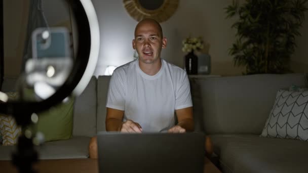 De jonge Spaanse man die video opneemt spelend videospel zittend op bank thuis - Video