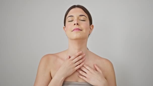 Jonge mooie latino vrouw glimlachen zelfverzekerde masserende huid nek over geïsoleerde witte achtergrond - Video