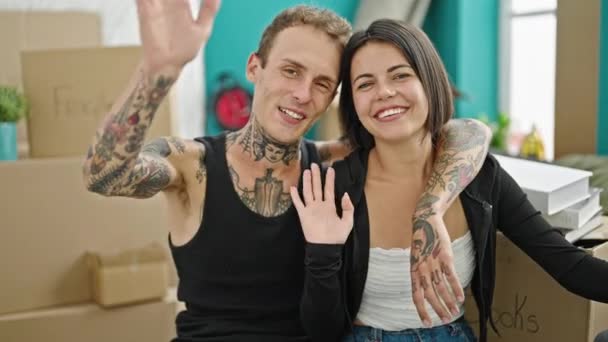 Bella coppia che si abbraccia dicendo ciao con mano sorridente a nuova casa - Filmati, video