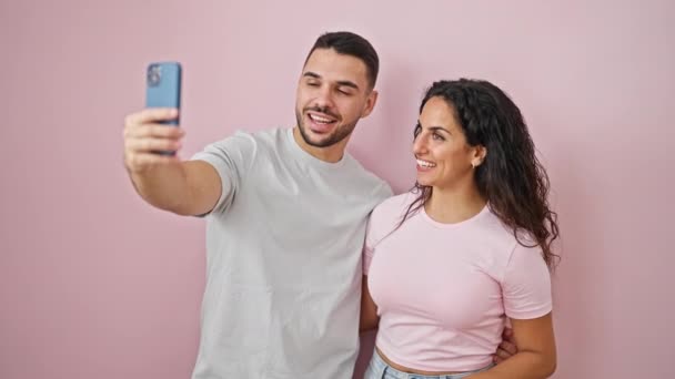 Чоловік і жінка пара мають відеодзвінок, посміхаючись над ізольованим рожевим тлом - Кадри, відео
