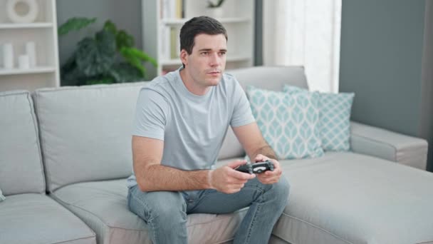 自宅でソファーに座ってビデオゲームをプレイする美しいカップル - 映像、動画