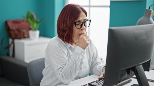 Keski-ikäinen nainen liiketoiminnan työntekijä, joka käyttää tietokoneen yskimistä toimistossa - Materiaali, video