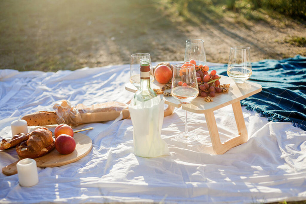 Gölün kenarında meyveler, hamur işleri ve şarapla güzel bir sonbahar pikniği. Güneş ışınları. - Fotoğraf, Görsel