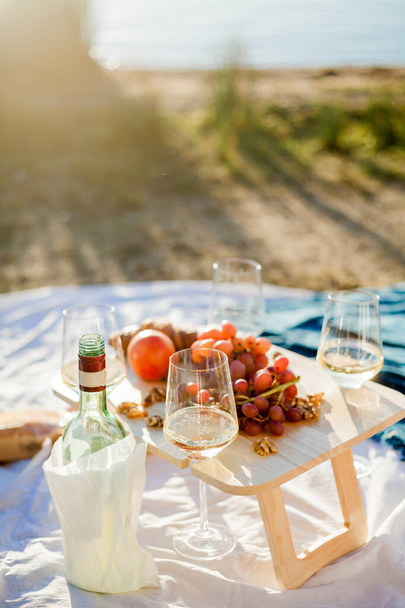 Bellissimo picnic autunnale vicino al lago con frutta, dolci e vino. Raggi solari. - Foto, immagini