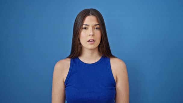 Νεαρή όμορφη ισπανόφωνη γυναίκα προσεύχεται πάνω από απομονωμένο μπλε φόντο - Πλάνα, βίντεο