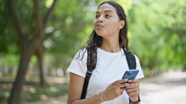 Afrikkalainen amerikkalainen nainen turisti käyttää älypuhelin yllään reppu puistossa - Materiaali, video
