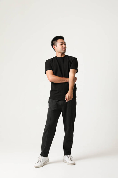 Handsome Asian young man posing over white background wearing black clothing. High quality photo. - Valokuva, kuva