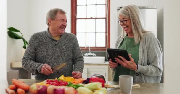 Old couple in kitchen, cooking with tablet and help, online recipe for vegetables and conversation. Healthy food, senior man and woman in home with digital app on meal prep, diet and lunch discussion. - Footage, Video