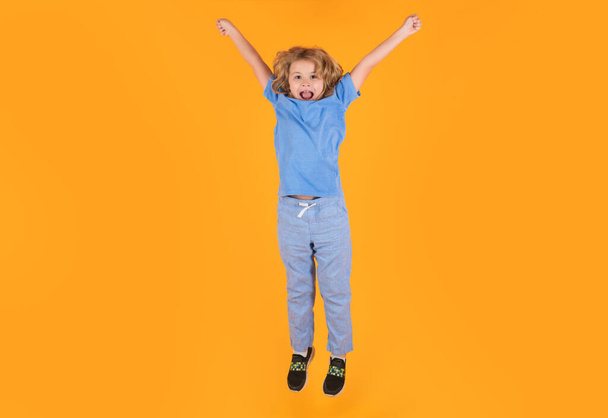 Funny boy jumping. Kid boy 8-9 years old in t-shirt jump isolated on yellow background. Childhood lifestyle concept. Mock up copy space. Kid having fun, jumping - Photo, Image