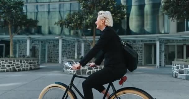 Zakenvrouw, gelukkig en fietsend naar het werk, gezondheid en welzijn. Volwassen persoon, glimlach en woon-werkverkeer of vervoer naar kantoor, actief en cardio in milieuvriendelijke, fiets en CO2-neutrale voetafdruk. - Video