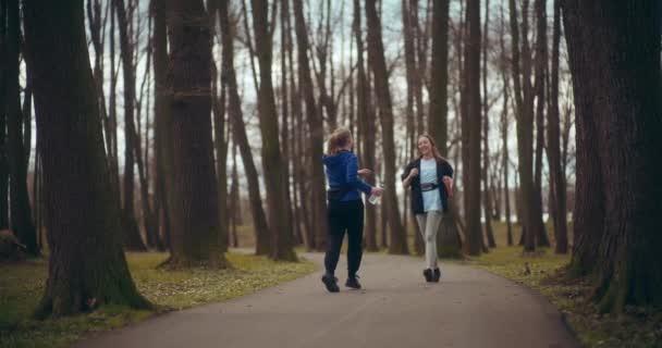 公園の道で互いに抱き合う幸せな若い女性の友人 - 映像、動画