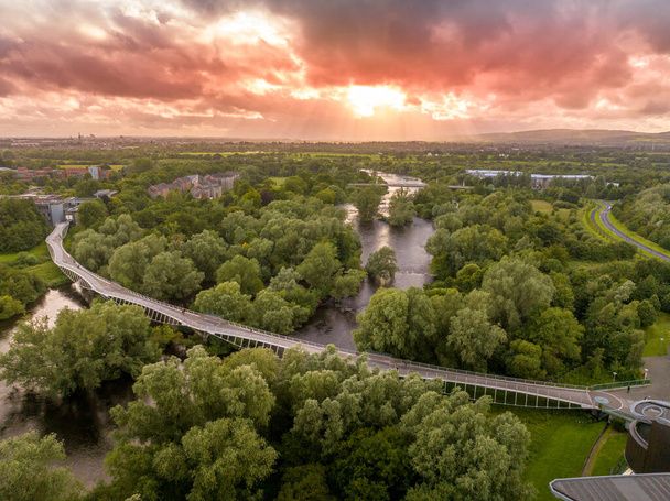 Vista panorámica aérea del Puente Viviente, curvo moderno paso peatonal sobre el río Shannon en la Universidad de Limerick con impresionante puesta de sol - Foto, Imagen