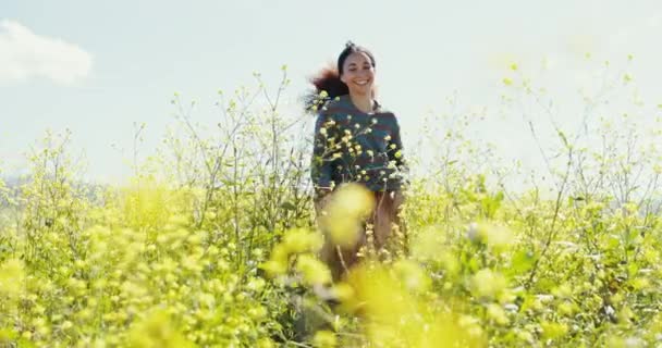 Mujer en campo de flores con sonrisa, corriendo con libertad y energía, excitada y despreocupada diversión primaveral. Naturaleza, plantas y chica feliz en el campo verde con estilo de vida boho pueblo con cielo azul - Metraje, vídeo