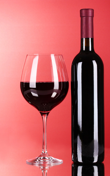 láhev vína a skla na červeném pozadí - Fotografie, Obrázek