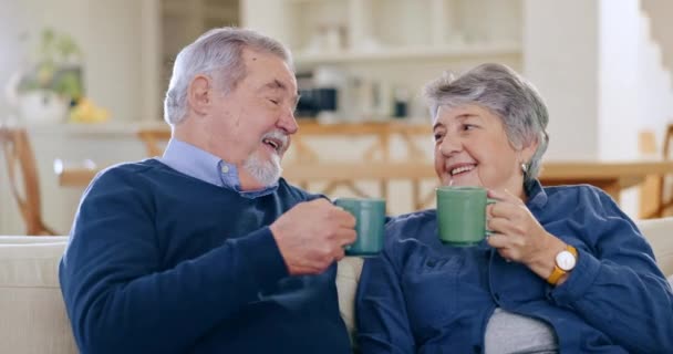 Happy, coffee and senior couple in conversation in the living room of modern home together. Smile, cheers and elderly man and woman in retirement talking, relaxing and drinking latte in the lounge - Footage, Video