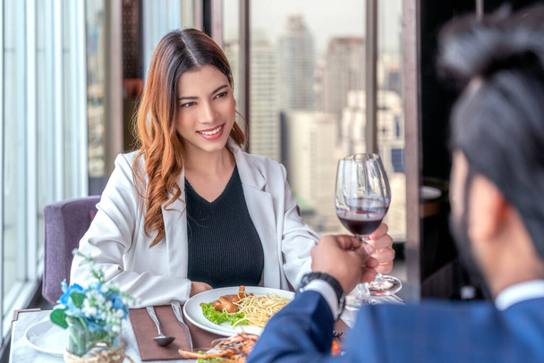 Asyalı çift sevgilisiyle çıkıyor ve otelin çatısındaki İtalyan restoranında masanın üstünde spagetti ile bir yudum alıyor. - Fotoğraf, Görsel