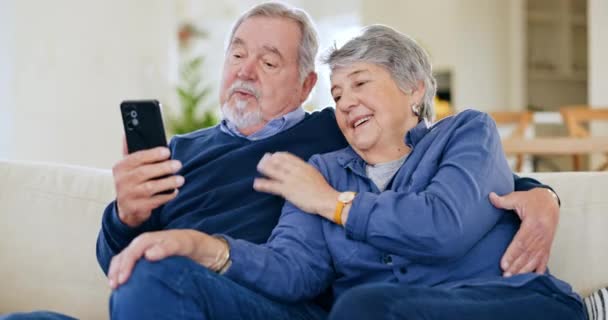 Senior, zamávat a pár s telefonem pro video hovor na pohovce s objetím, komunikace a štěstí v obývacím pokoji. Starší, muž a žena s chytrým telefonem na gauči s pozdravem on-line pro konverzaci. - Záběry, video