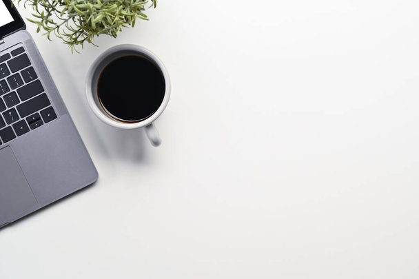 Een kopje koffie, laptop en potplant op witte achtergrond. Bovenaanzicht met kopieerruimte. - Foto, afbeelding