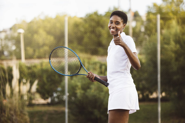 Fiatal, gyönyörű, mosolygós nő teniszezik. Sportos nő egy teniszütő játszik szabadtéri teniszpálya. - Fotó, kép
