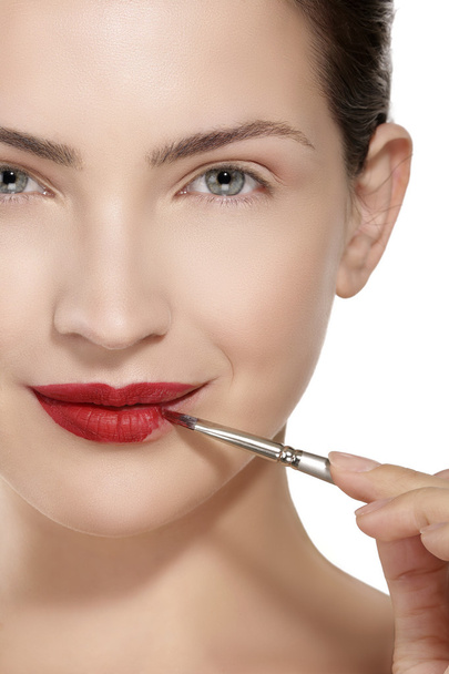 Beauty model applying red lipstick with brush - Φωτογραφία, εικόνα