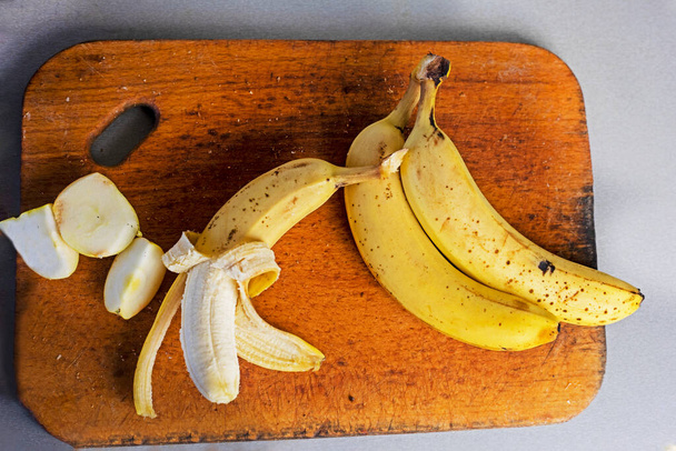 mazzo di banane con fette di mela su un tagliere di legno su sfondo grigio. flatlay - Foto, immagini