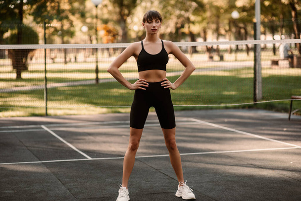 A young female trainer performs a fitness compression exercise. The girl is working out outdoors. Healthy lifestyle. High quality photo - Fotó, kép