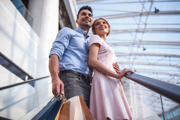 schönes Paar mit Einkaufstaschen spricht und lächelt beim Einkaufen in der Mall - Foto, Bild