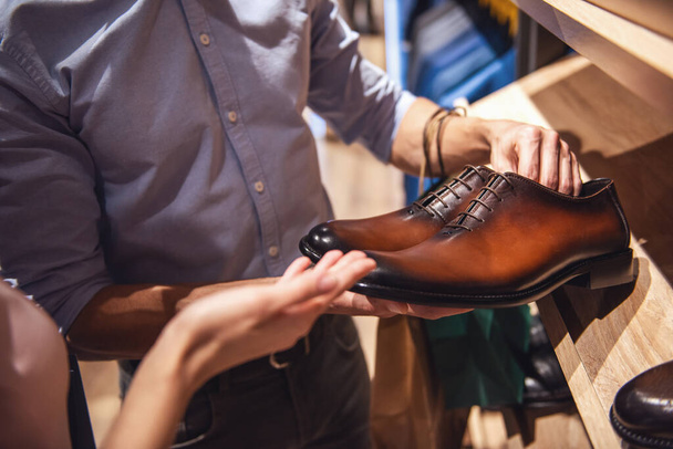 Bijgesneden afbeelding van mooie paar klassieke schoenen kiezen terwijl het doen van winkelen in de mannelijke winkel - Foto, afbeelding