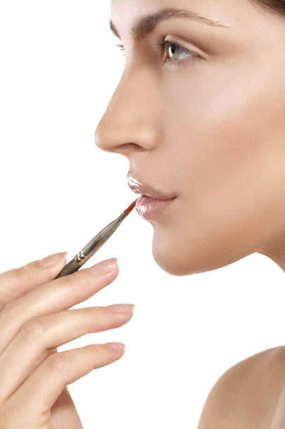 Beautiful model applying lip gloss with a brush - Φωτογραφία, εικόνα