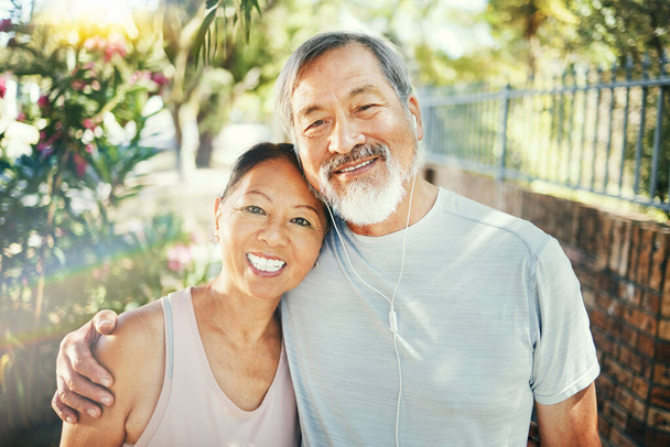 Hug, outdoor and senior couple with exercise, portrait and retirement with workout, smile and love. Park, elderly man and happy old woman embrace, face and fitness with summer, wellness and health. - Photo, Image