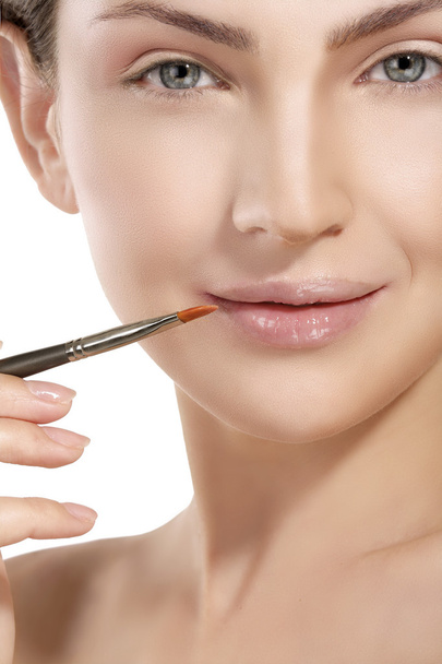 Beautiful model applying lip gloss with a brush - Foto, immagini