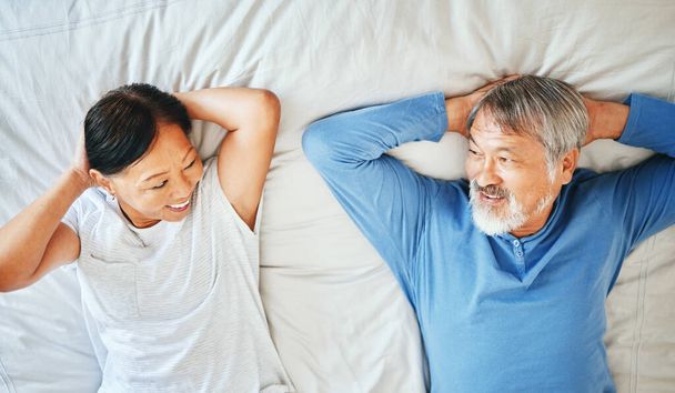 Ágy, arc és érett ázsiai pár alszik, fáradt vagy szundikál partner ellátás, reggeli wellness vagy nyugdíj. Top view, mosoly és idős nő, férfi vagy házasság emberek szemkontaktus Japánban otthoni hálószoba. - Fotó, kép