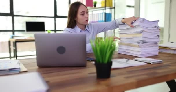 Mujer cansada molesta mirando una gran pila de documentos de trabajo. Horas extraordinarias y exceso de trabajo - Metraje, vídeo
