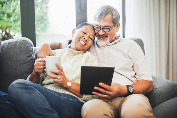 Tablet, Kaffee und Seniorenpaar auf dem Sofa, entspannen sich und vernetzen sich gemeinsam in den sozialen Medien. Glückliche, digitale Technologie und ältere Männer und Frauen im Ruhestand scrollen auf mobilen Apps oder im Internet - Foto, Bild