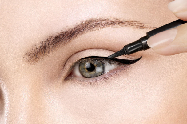 Beautiful model applying eyeliner closeup on eye - Foto, afbeelding
