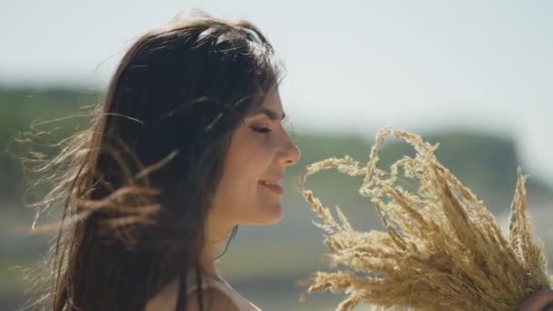 Happy woman sniffing flowers. A carefree girl enjoys the freedom and peace of nature while on vacation. The concept of rest and happiness - Footage, Video