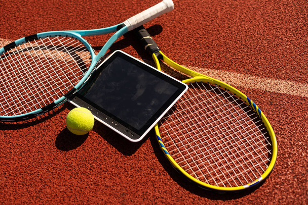 Високий кут зору тенісної ракетки і м'яча за допомогою цифрового планшета на фоні морської піхоти. Високоякісна фотографія - Фото, зображення