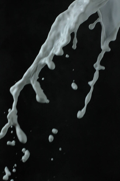 salpico de leite em um copo em um fundo preto. salpicos de leite. - Foto, Imagem